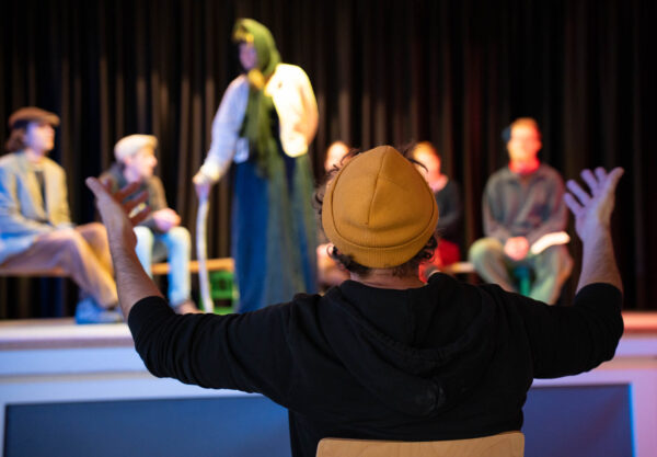 Theaterpädagoge Simon Pflanzer leitet eine Probe mit Jugendlichen auf der Bühne